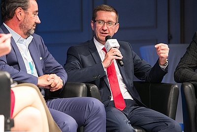 v.l: Andreas Berger (Senior Vice President HR, Rosenbauer International AG) und Wirtschafts-Landesrat Markus Achleitner diskutieren am Podium über die Attraktivität des Standortes Oberösterreich für internationale Fachkräfte. © Cityfoto/Roland Pelzl